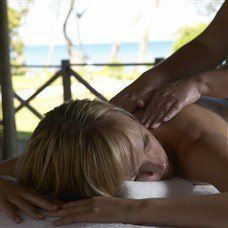 woman being massaged with sea behind her in lakitira