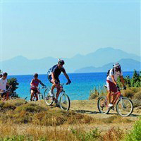 people cycling up a hill with view behind in lakitira